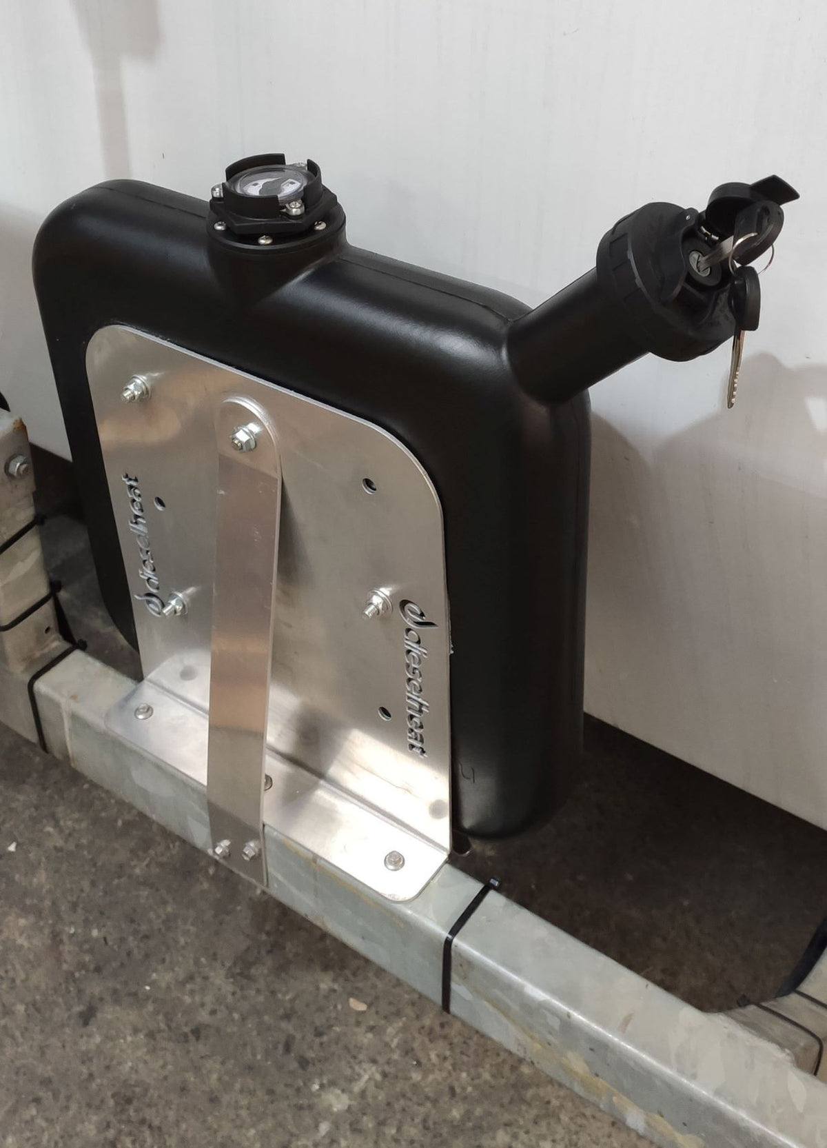 Fuel tank with metal bracket attached to a vehicle frame against a white background