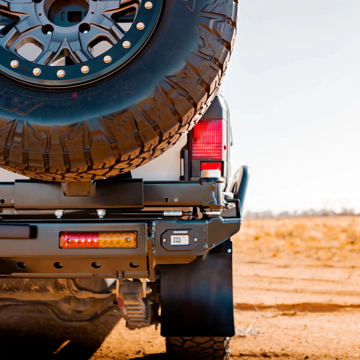 Close-up of a vehicle's rear with a spare tire mounted on a desert landscape – TCC 78 Series Troop carrier Rear Bar Tow Bar