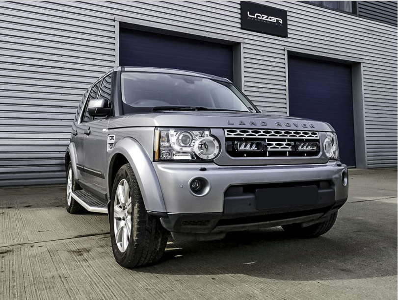 Silver Land Rover parked in front of a building with 'Latan' branding.