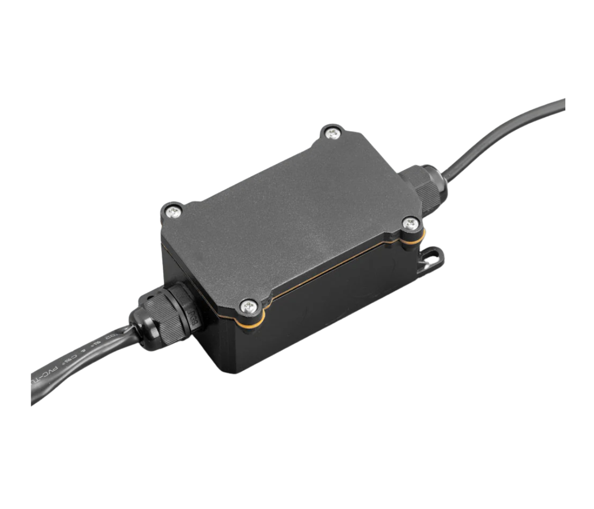 Sealed control box for the rock light kit, a black moulded housing with a screwed-down lid, an orange gasket line around the seam, cable glands at each end and a mounting lug on one corner