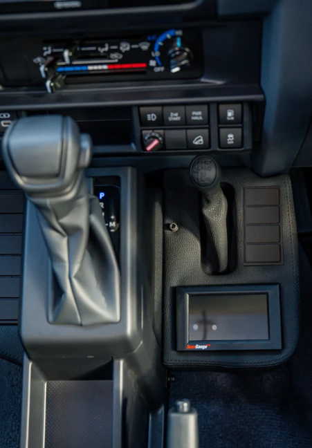 Close-up of a car's gear shift and dashboard controls.