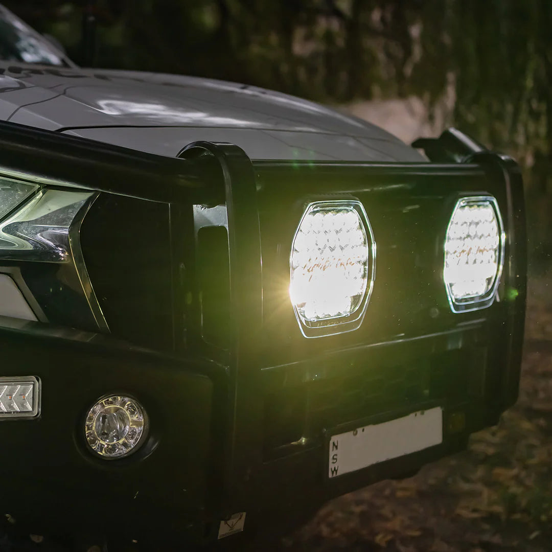 Pair of Lightforce BEAST driving lights switched on at night, mounted to a 4WD bullbar in bushland