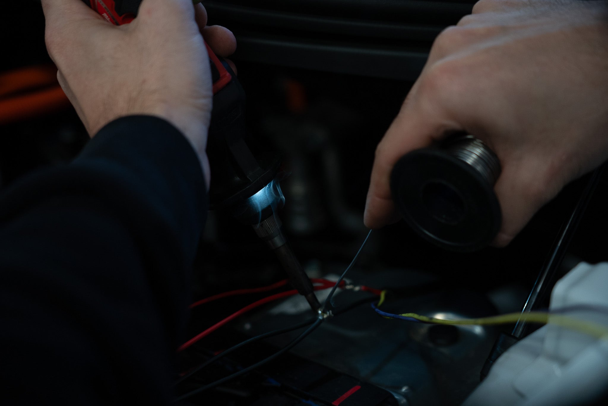 Person working with wires and tools on a dark background