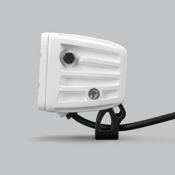 White DX4 Scene work light in profile from the rear, the ribbed white housing with two adjustment screws and the black bracket beneath carrying the lead