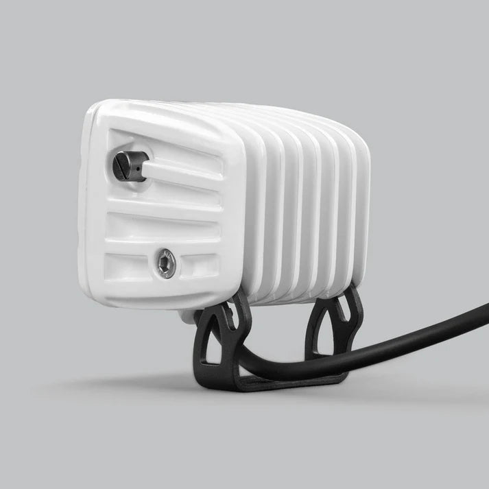 White DX4 Scene work light seen from the side, the ribbed white housing with its adjustment screw and the black mounting bracket with the lead running behind