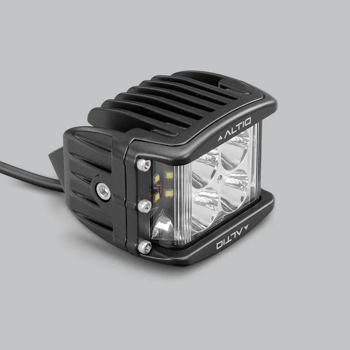 DX4 hybrid work light at a three-quarter angle, showing the round spot optics and the side flood strip together behind the clear lens