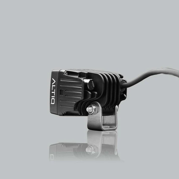 ALTIQ CX2 work light from the opposite side, the ALTIQ name on the housing with the mounting bracket bolted through and the lead running away behind