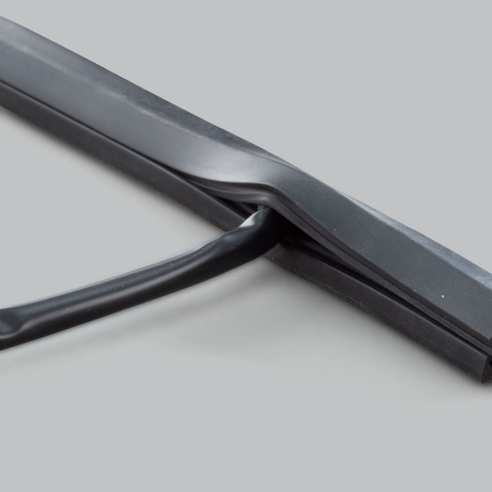 The wire concealer with a cable emerging from the slot in its underside, showing how the channel closes over the wire