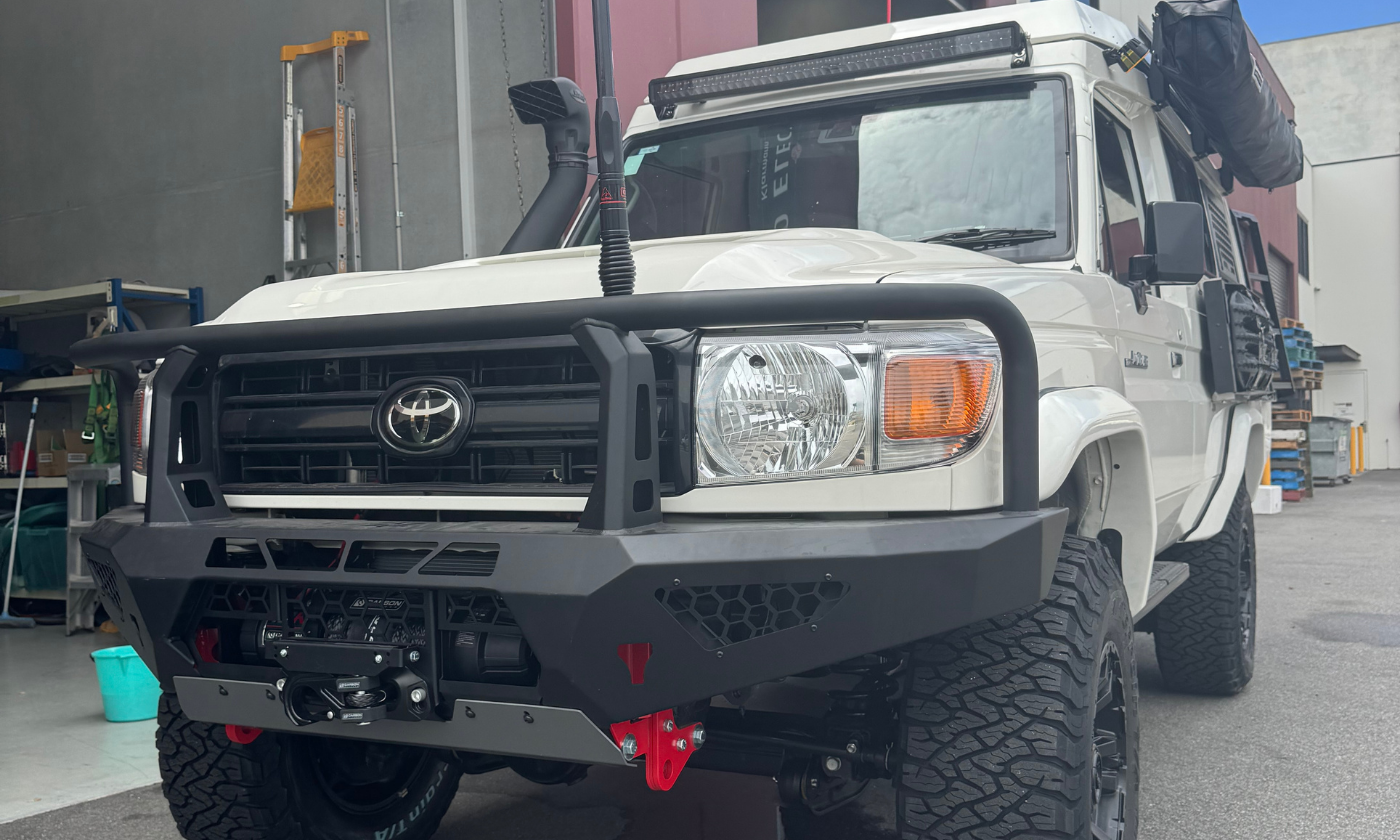 White Toyota truck with large black bumper in front of a building