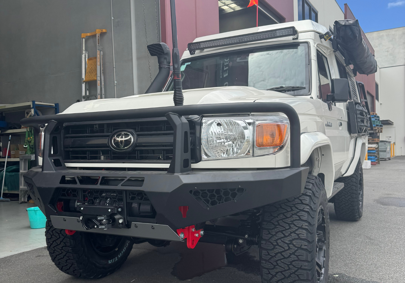 White Toyota truck with large black bumper in front of a building