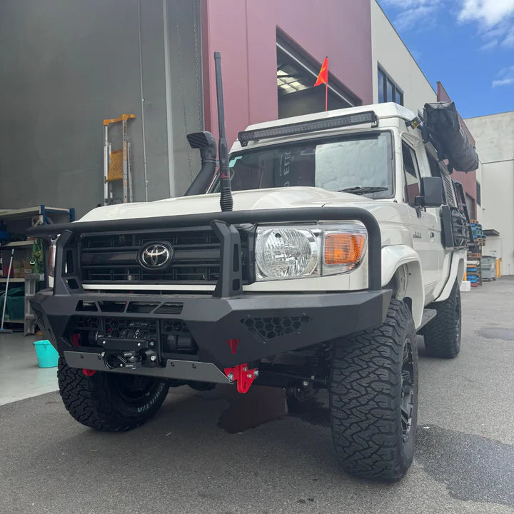 White Toyota truck with large black bumper in front of a building