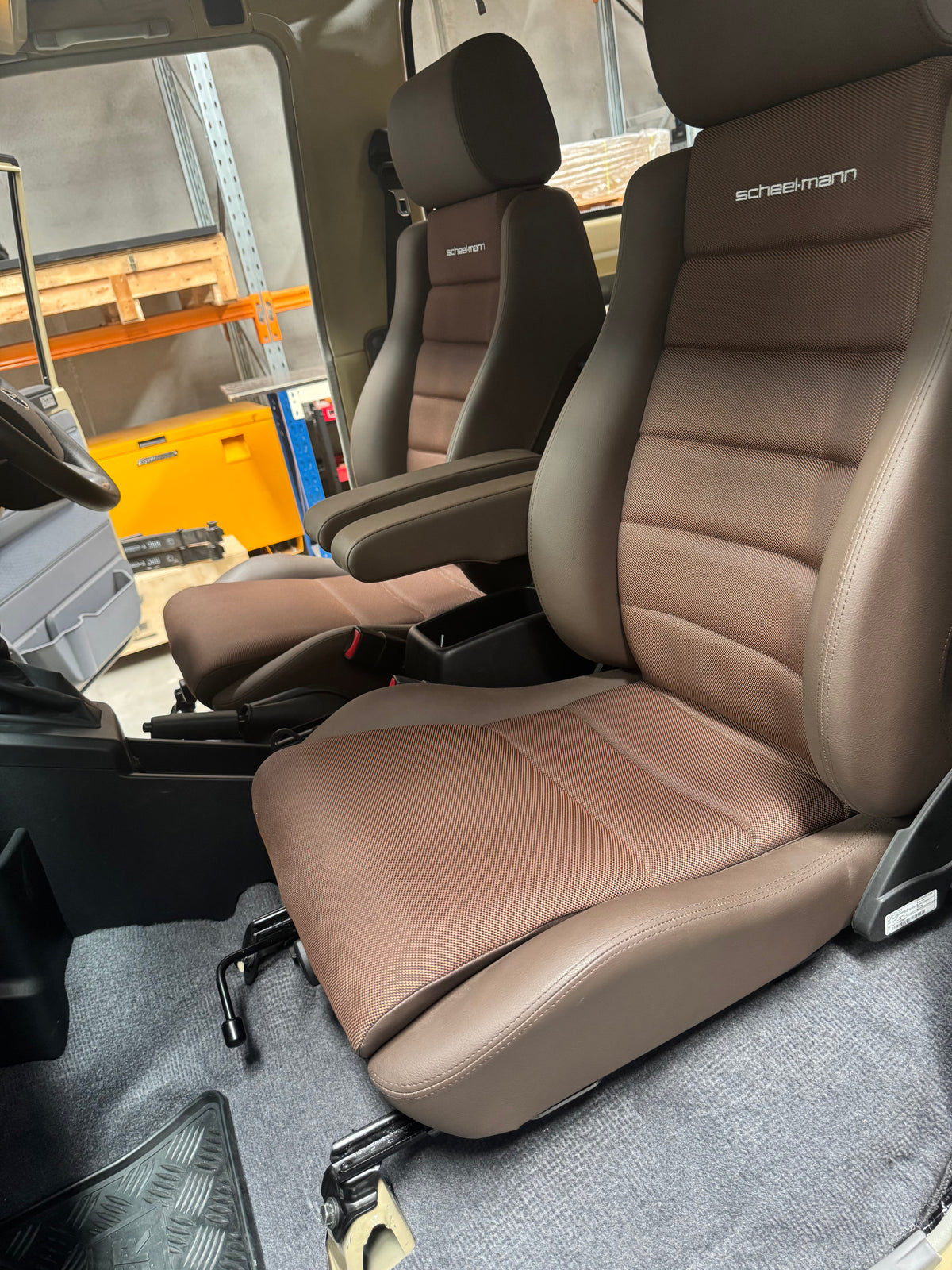 Beige car seat with visible Scheelmann branding in a workshop setting