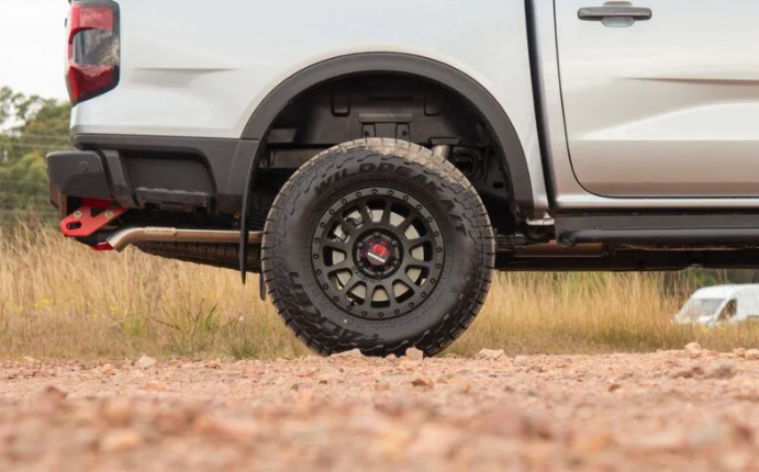 Close-up of a white truck with off-road tires on a dirt road