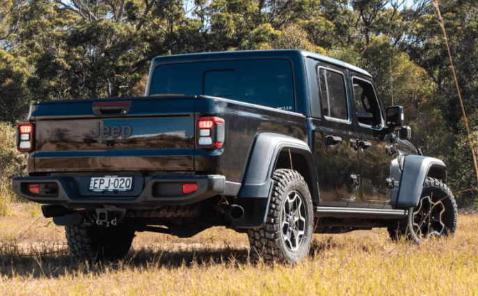 Black Jeep truck in a natural setting with trees and grass.
