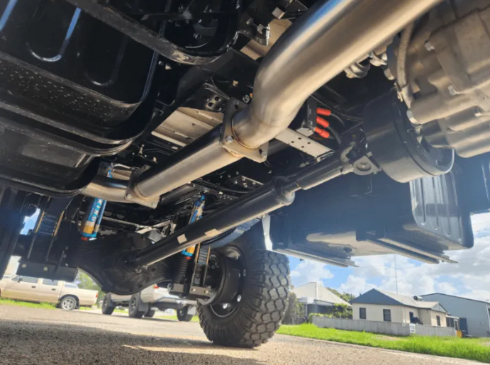 Close-up of a vehicle's undercarriage with visible suspension components on a road.