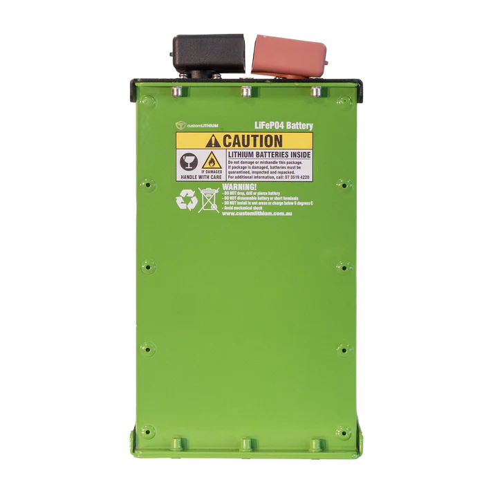 A Custom Lithium slim LiFePO4 battery in a bright green case standing on end, the black and red terminal covers on top and the caution label across the upper face