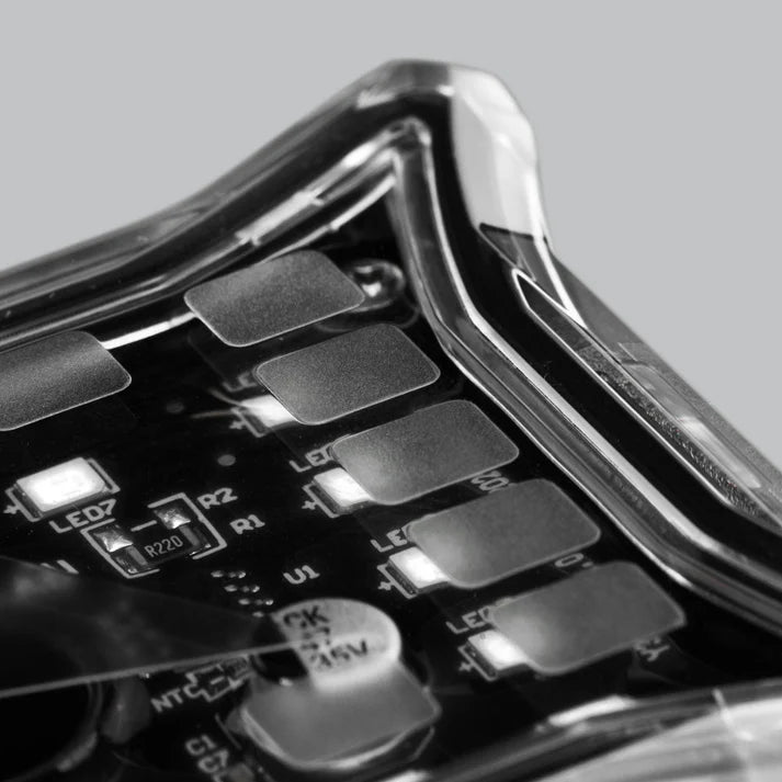 Close-up across the corner of a rock light, the clear lens curving away over the LED board with individual LEDs and the 47 microfarad capacitor in focus