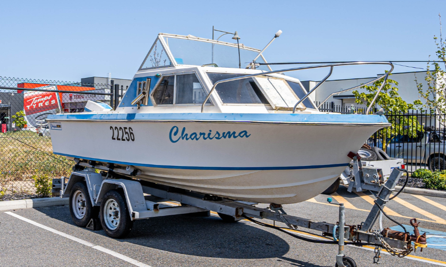 Boat on a trailer in a parking lot with a clear blue sky