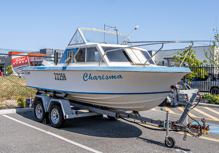 Boat on a trailer in a parking lot with a clear blue sky
