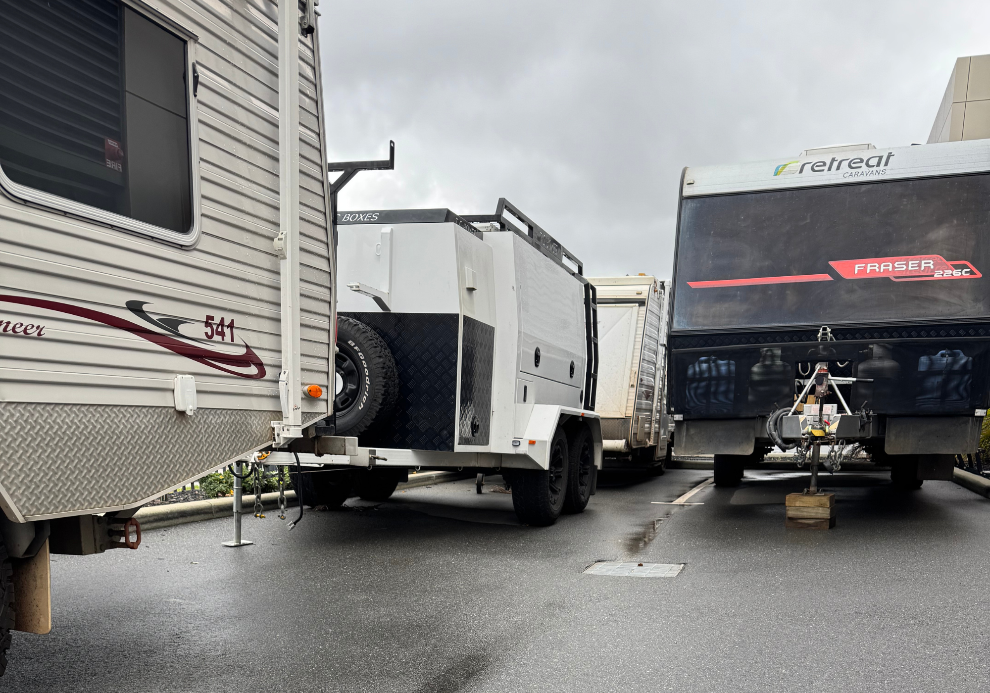 Two travel trailers in a parking lot with a cloudy sky
