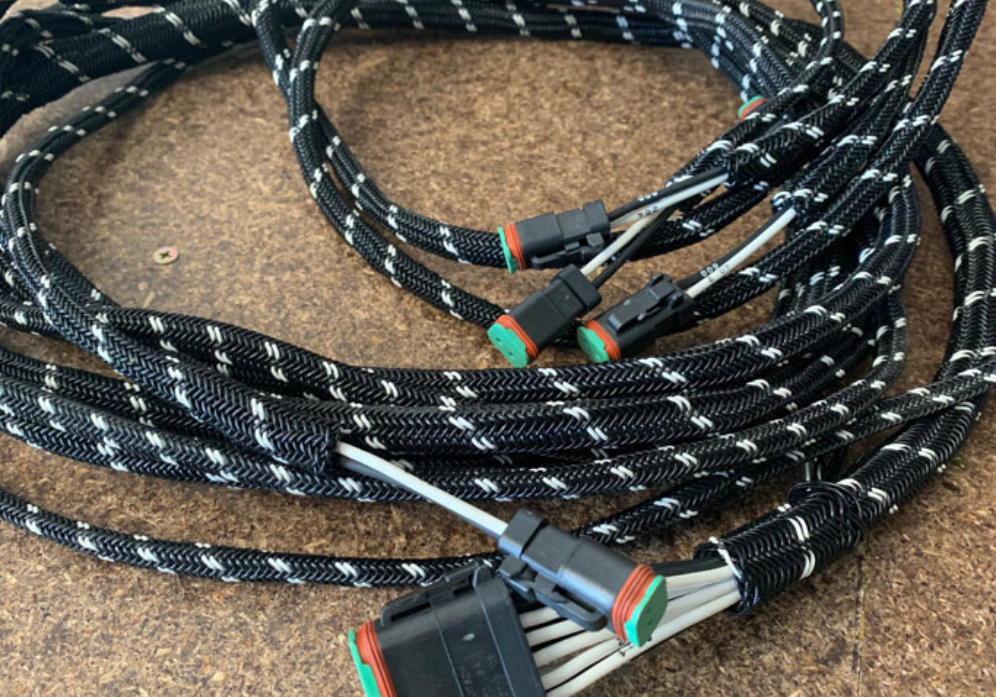 Coiled black and white cable with connectors on a brown surface