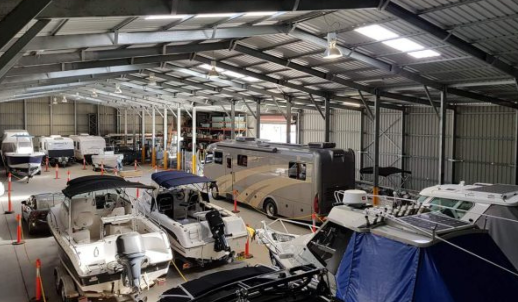 Storage facility with various vehicles including boats and RVs.