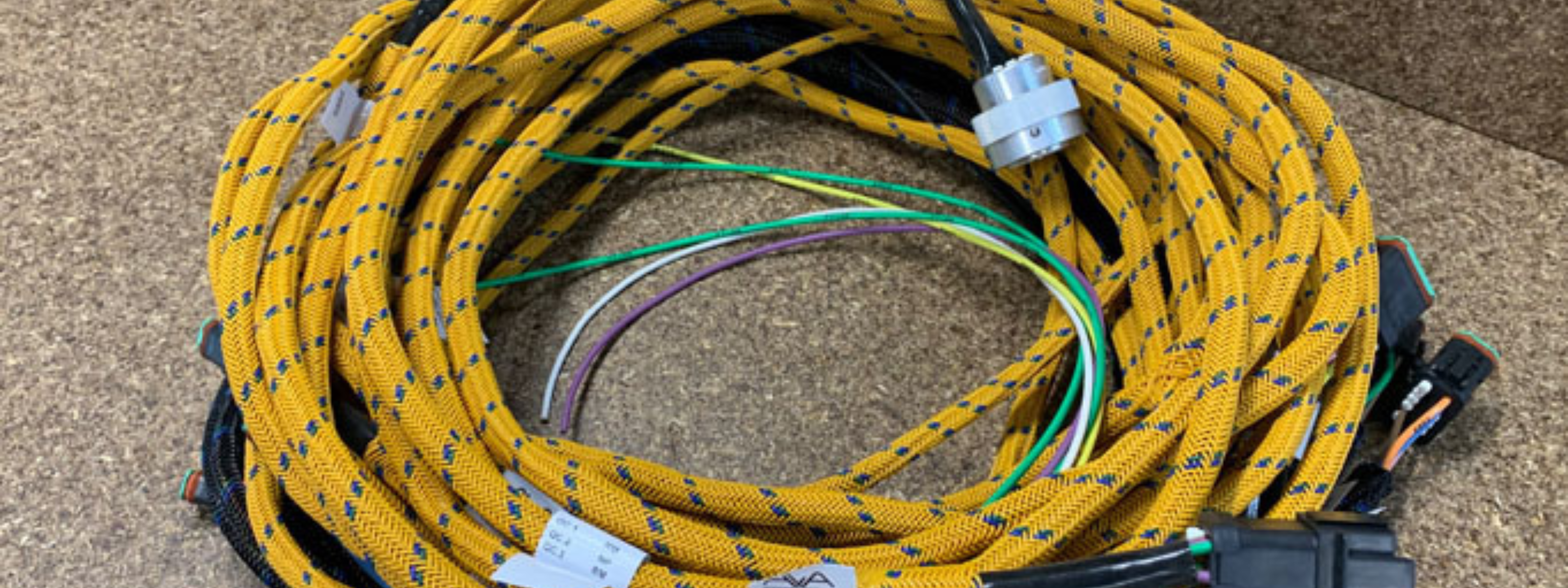 Coiled yellow cable with electrical connectors on a textured surface