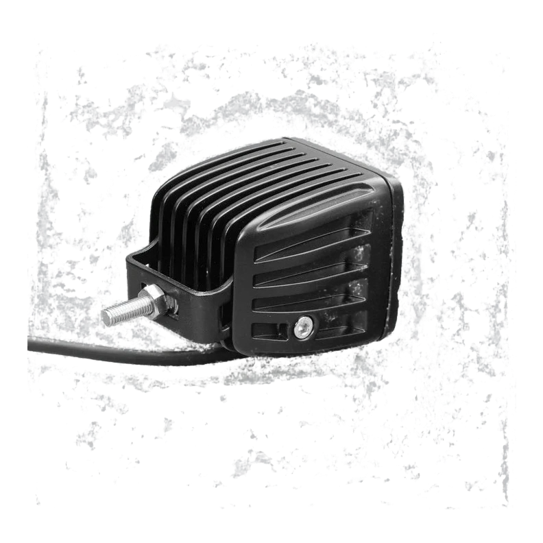 DX4 work light from above and to the side, showing the deeply finned cast heatsink, the stainless mounting bracket and threaded stud, and the lead leaving the rear