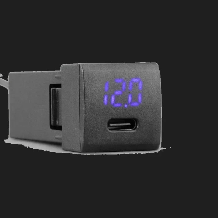 ALTIQ panel-mount USB-C voltmeter module with a blue seven-segment display reading 12.0, shown at an angle with the black moulded body and mounting shoulder behind