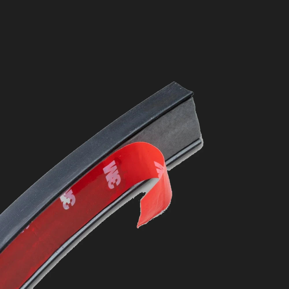 End of the wire concealer with the red 3M adhesive backing tape partly peeled away from the underside of the black moulded channel