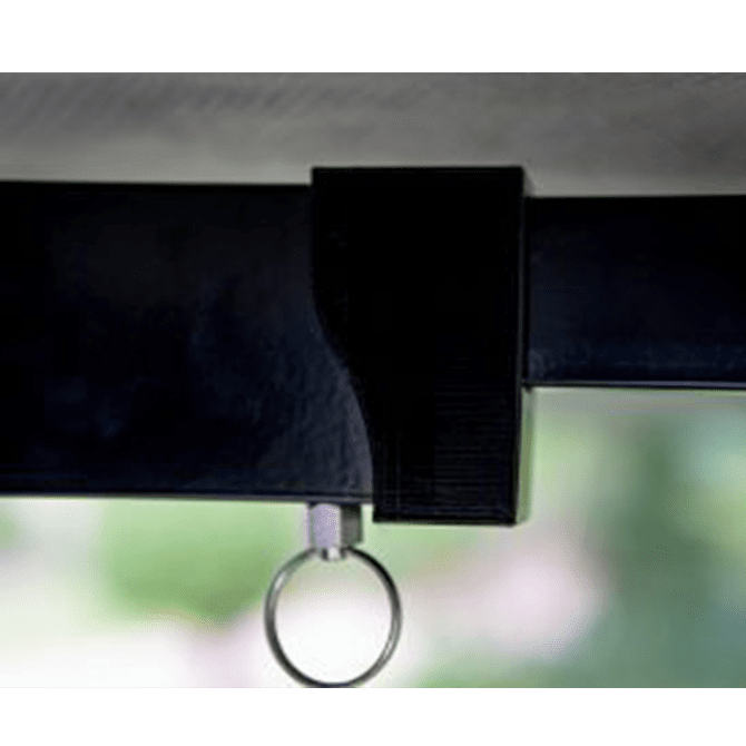 Close-up of a black strap with a metal ring attachment against a blurred green background