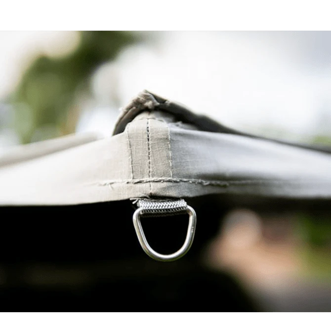 Close-up of a tent strap with a metal ring against a blurred natural background