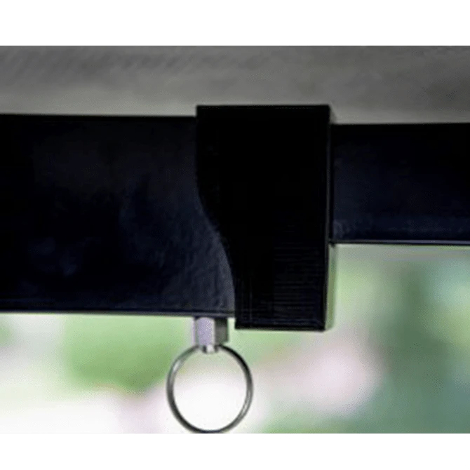 Close-up of a black strap with a metal ring attachment against a blurred green background