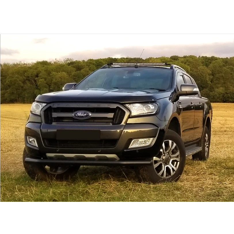 Black Ford parked in a field with trees in the background with Lazer Lamps Roof Mount Kit – Ford Ranger (2016–2022 with Roof Rails)