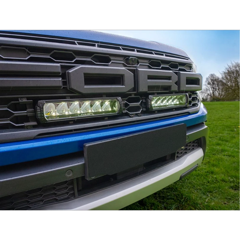 Close-up of a Ford truck grille with LED lights on a grassy background