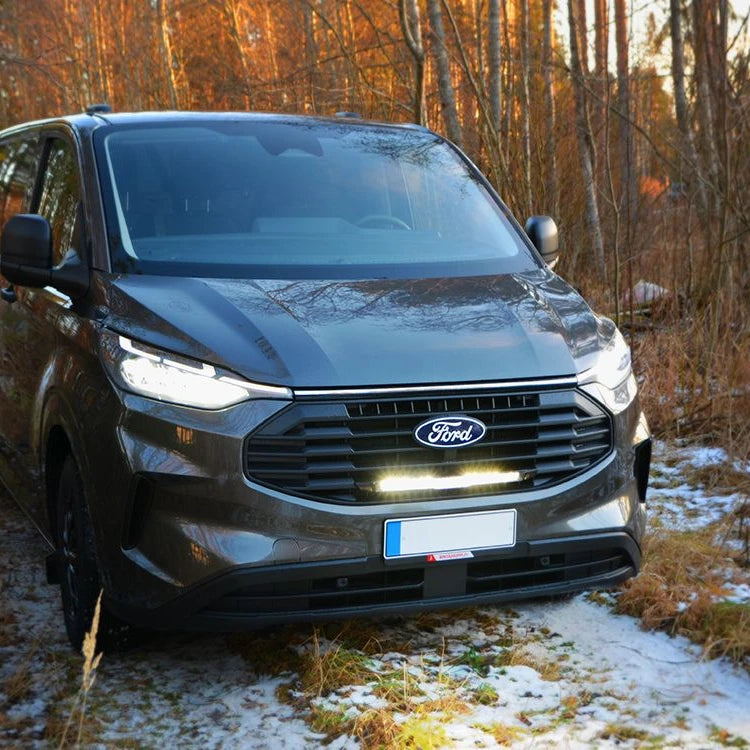 Ford Transit Custom (2024+) with the Lazer grille kit and Glide light bar fitted, parked in a forest clearing