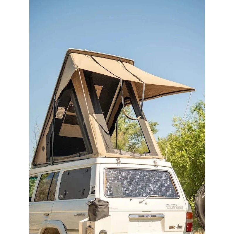 White SUV with a beige rooftop tent set against a clear blue sky – Headspace Roof Conversion LC60