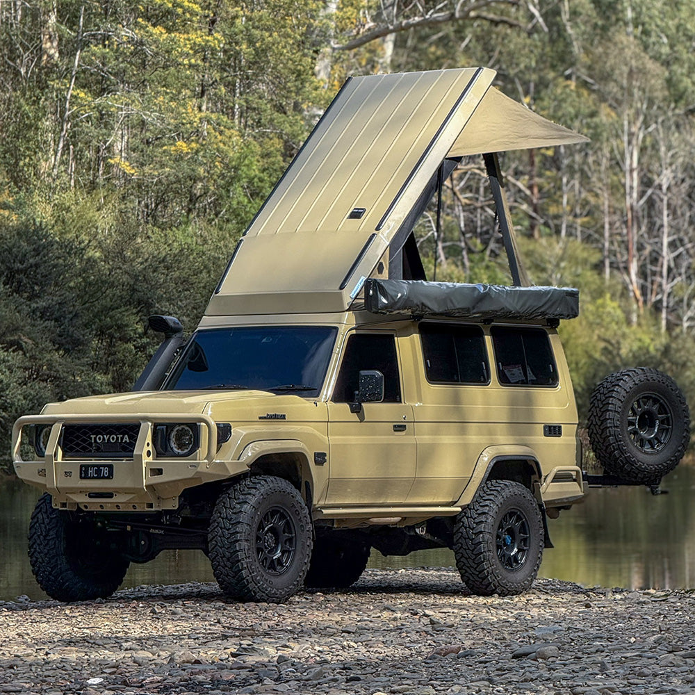 Beige 78 Series Troopy with the Headspace roof raised, parked near water