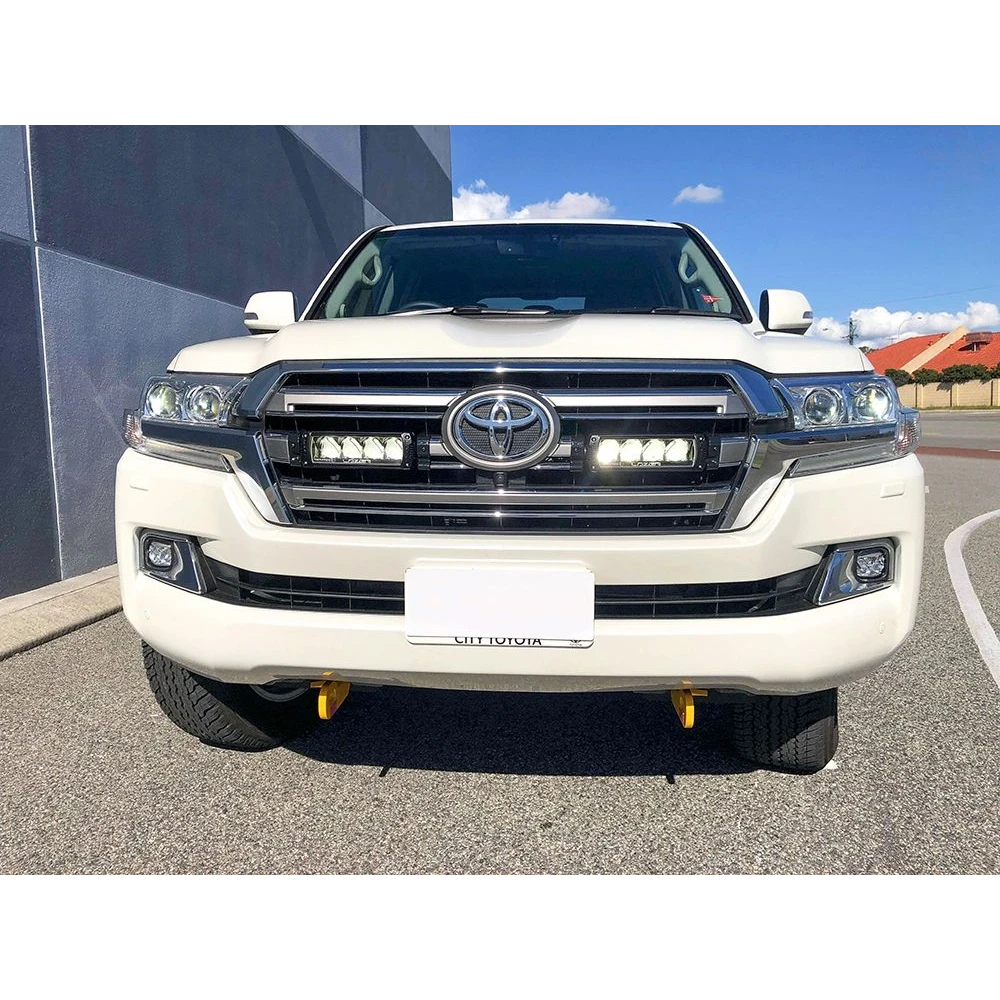 White Toyota 200 series parked on a street with a building in the background with Lazer Lamps Grille Kit – Toyota Land Cruiser 200 Series (2015–2021)