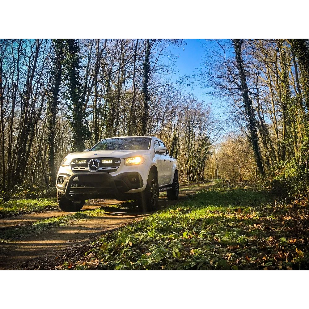 Lazer Lamps Mercedes X-Class (2017+) Grille Kit – white Mercedes-Benz ute driving on a forest path with trees and grass on either side.