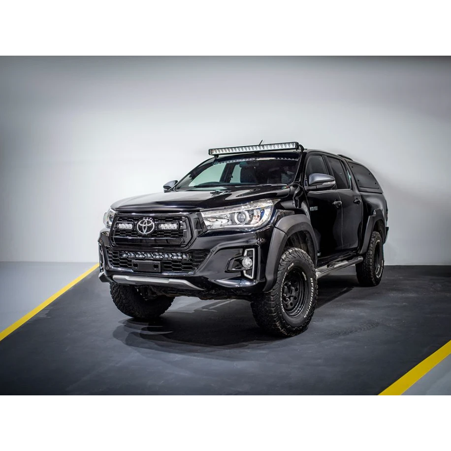 Black Toyota pickup truck with additional lights on a gray background