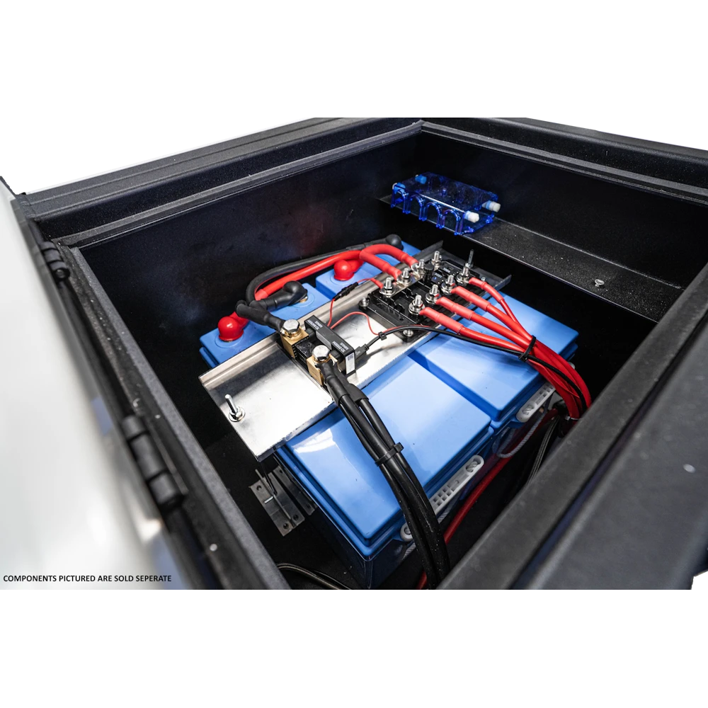 Two lithium batteries installed inside the compartment in a vehicle drawer, wired to a busbar and shunt on a mounting rail with a fuse block beside them. Caption on the image notes the components pictured are sold separately