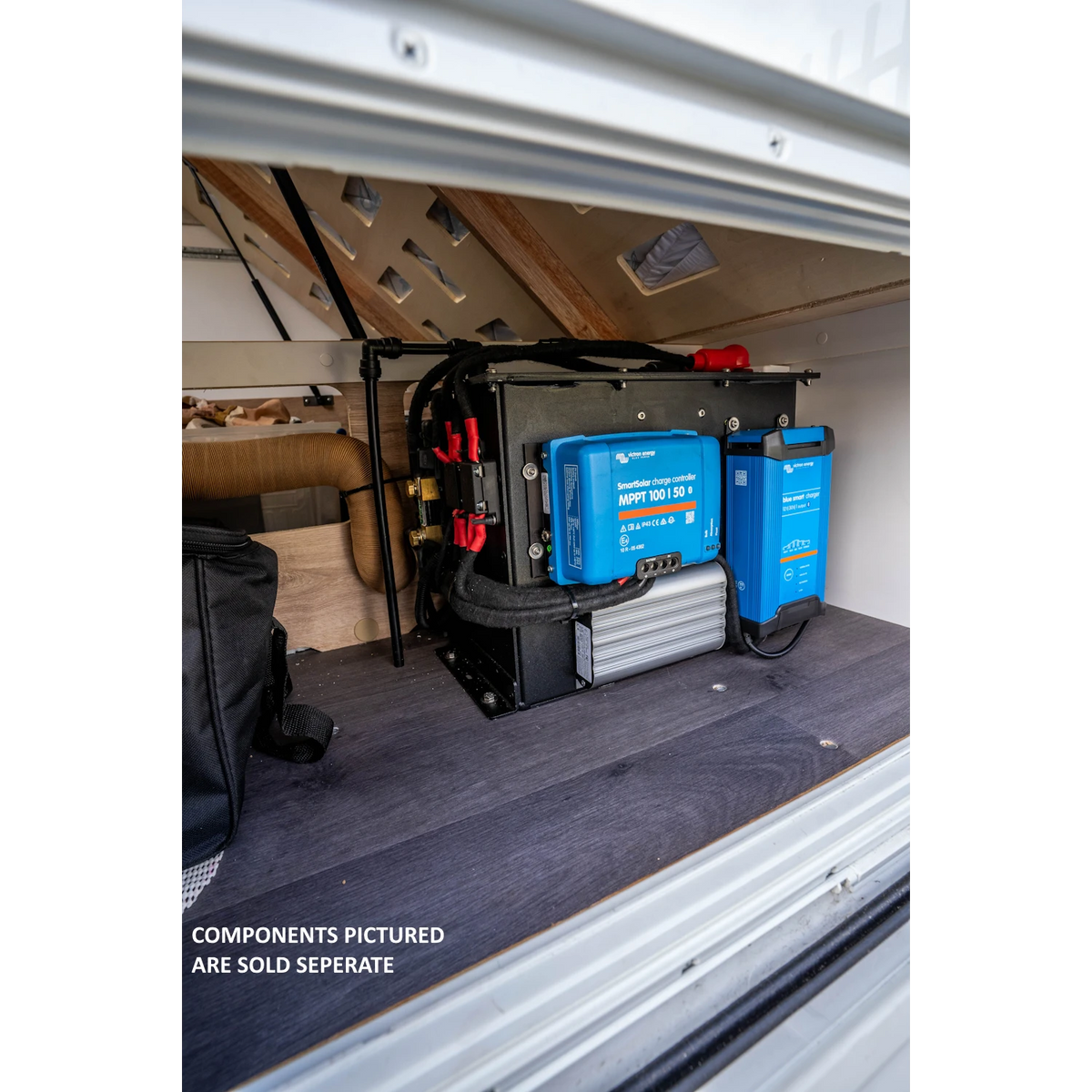 The lithium battery compartment mounted on its side under a bed platform in a van, with a Victron SmartSolar MPPT 100/50 charge controller and a Victron Blue Smart charger fixed to its outer face