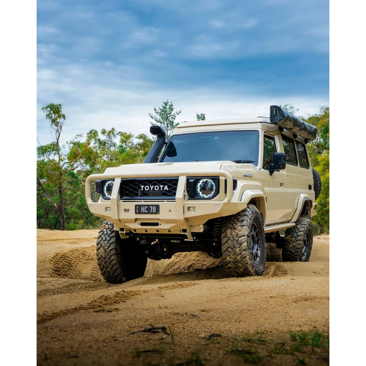 sandy Toyota off-road vehicle on a dirt road with trees in the background – TCC 70 Series Bull Bar - Facelift (2024 - Present)