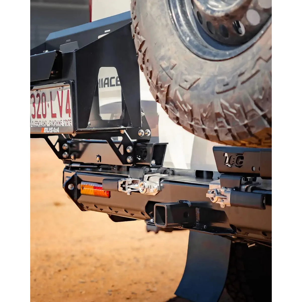 Close-up of a vehicle's hitch receiver with a tire in the background – TCC Toyota Hiace 300 Series Rear Bar