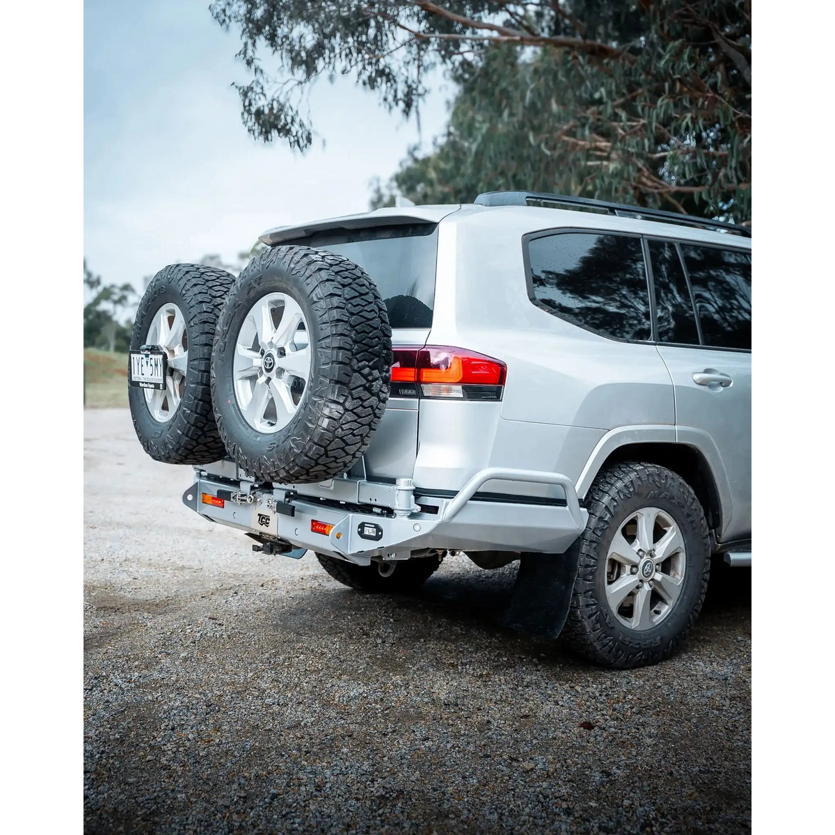 Silver SUV with a spare tire on a hitch, parked outdoors with trees in the background – TCC Toyota LC300 Series Rear Bar