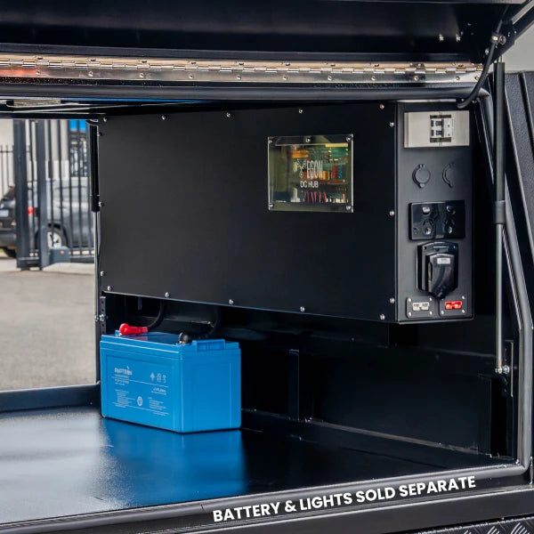 The Prospector canopy power system installed in a ute canopy, showing the EGON DC Hub viewing window, 240V outlets and 12V sockets on the end face, with a battery on the canopy floor