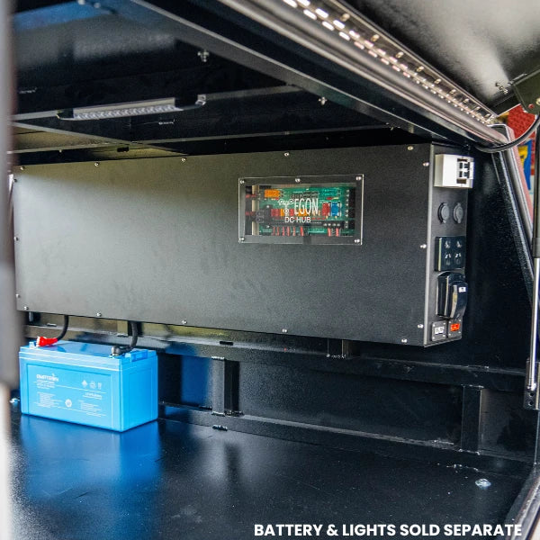 The Prospector fitted along the wall of a ute canopy with the EGON DC Hub window visible, a battery on the floor below and LED strip lighting overhead