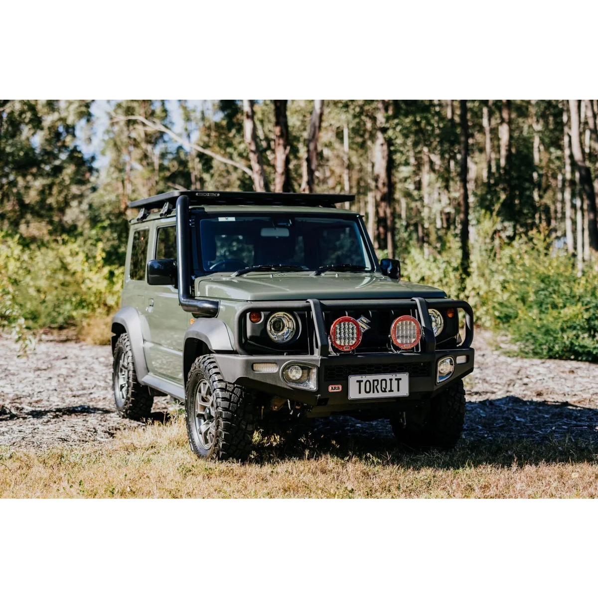 Green Suzuki Jimny with Torqit plate and snorkel in a forest setting – Torqit 3.5" Stainless Steel Snorkel (Matte Black) for Suzuki Jimny (JB74 / JC74 XL)