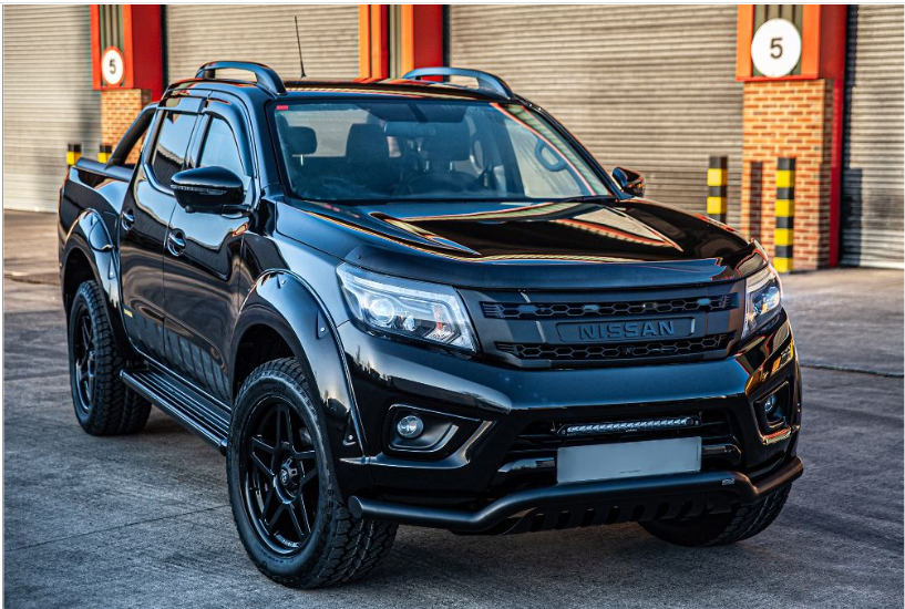 Black Nissan truck parked in front of a building with a red door with Lazer Lamps Nissan Navara (2014-2021) Kit